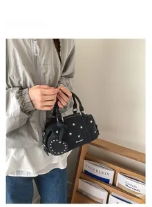 Detail der schwarzen Bowlingtasche mit Sternnieten und Herzanhänger in Lifestyle-Szene
