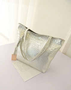 Gros plan sur un sac cabas argenté métallisé avec texture crocodile et doubles anses
