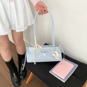 Détail d'un sac floral avec ruban de dentelle, pendentif cœur et breloque lapin