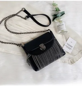 Close-up of black PU leather bag with metallic fringe tassels and bronze buckle closure