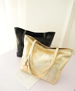 Détail de sacs fourre-tout à motif crocodile en or et noir avec textures métallisées