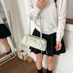 Détail du sac baguette vert menthe avec imprimé floral, nœud et charme de lapin