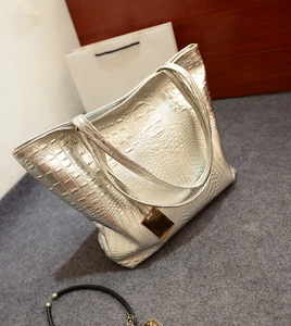 Détail d'un sac cabas argenté motif crocodile avec ornement métallique doré chic