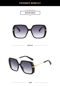 Detail view of square oversized black frame sunglasses with golden metal hinges and gray lenses
