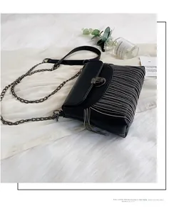 Detail of black faux leather crossbody bag with silver fringe tassels and metal chain
