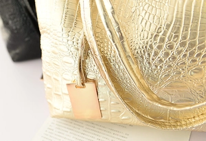 Gros plan sur un sac cabas doré en similicuir avec texture crocodile et bijou de sac