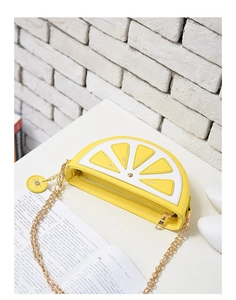 Detailed view of yellow lemon-shaped crossbody bag with gold chain and flower charm