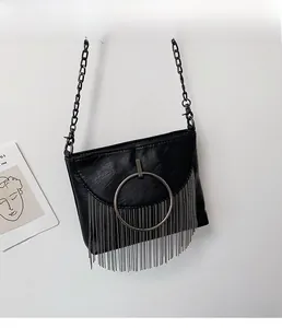 Detail of black PU crossbody bag with large silver ring and long metal tassels