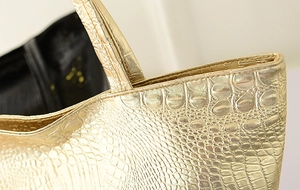 Détail du sac cabas doré avec texture crocodile gaufrée et finition métallique premium