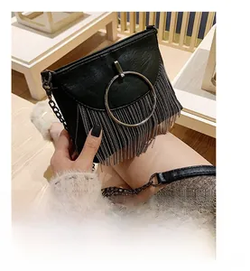 Detail of black faux leather crossbody bag featuring gold metal ring and chain tassel decoration