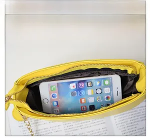Top view of yellow fruit-shaped crossbody bag interior with chain strap and phone for scale
