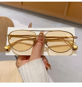 Dettaglio di occhiali da sole aviator vintage con montatura in oro e lenti gialle