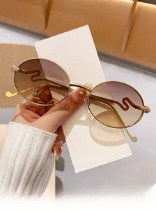 Détail macro de lunettes de soleil dorées avec branches ondulées et verres bruns dégradés
