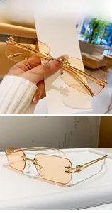 Detail of rimless rectangle sunglasses with gold cross accents and orange tinted lenses
