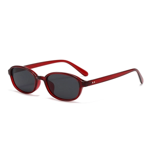 Stylish retro oval sunglasses with translucent red frames and dark grey lenses in 45-degree view