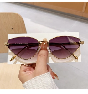 Detailed close-up of golden metal panther head embellishment on cat-eye sunglasses