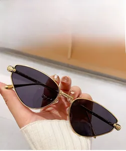 Detail of gold metal sunglasses with grey lenses and embossed leopard head on the temple