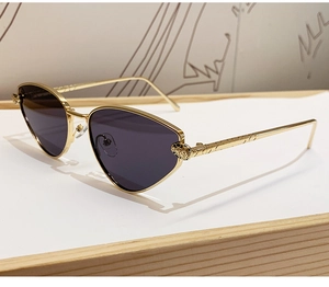 Detail of gold metal cat-eye sunglasses featuring an intricate leopard head ornament