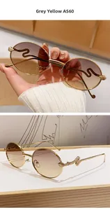 Détail de lunettes de soleil rondes avec branches dorées gravées de serpent et verres dégradés