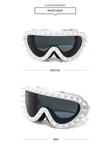 Detail view of white punk goggles with decorative spikes and adjustable elastic strap