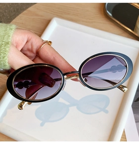 Détail de lunettes de soleil ovales avec verres dégradés violets et pont doré