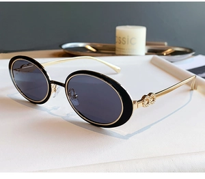 Détail de lunettes de soleil ovales rétro avec monture noire et branches dorées