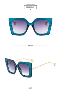 Detail view of square blue gray sunglasses with gradient lenses and gold metal temples