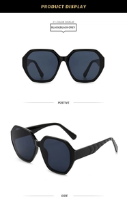 Close-up of oversized hexagonal black sunglasses with ribbed temples and grey lenses