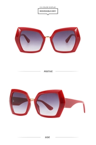 Detail view of red hexagonal oversized sunglasses with gold metal bridge and gradient lenses