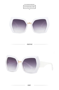 Detail of white geometric sunglasses with gradient lenses and gold metal bridge accents
