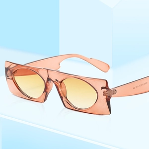 Retro amber rectangle sunglasses with yellow tinted lenses on a blue minimalist stand