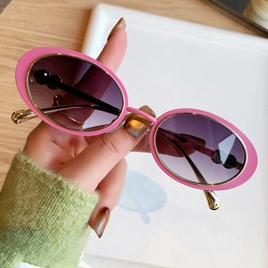 Lunettes de soleil ovales rétro avec monture rose et verres dégradés violets sur plateau