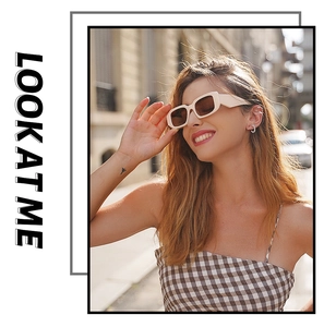 Detail of beige rectangle sunglasses with brown lenses worn by a model in soft street light