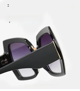 Detail of oversized square sunglasses featuring black frames and purple gradient lenses