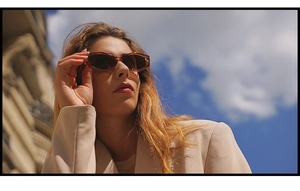 Retro tortoiseshell oval sunglasses worn against a blue sky and classic architecture