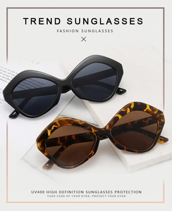 Close-up of geometric irregular sunglasses with black and tortoise frames on marble tray
