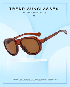 Detail of amber round frame sunglasses with UV400 protection on a blue podium stand