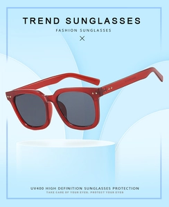 Detail of red square sunglasses with UV400 protection on a floating blue platform