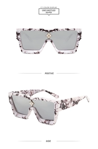 Detail view of grey mottled oversized square sunglasses with silver lenses and gold star decor