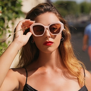 Occhiali da sole geometrici oversize con montatura rosa chiaro e lenti marroni su modella