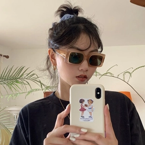 Fashionable amber square sunglasses with dark lenses worn by a model in a cozy indoor setting