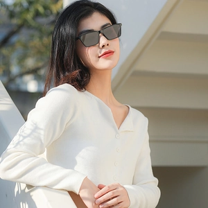 Minimalist black square sunglasses and white knit top shown in an outdoor street style shot