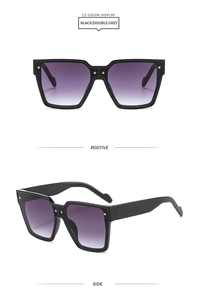 Détail des verres dégradés et rivets dorés sur lunettes de soleil noires oversize