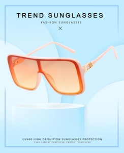 Detail of square oversized sunglasses with pink frame, orange gradient lenses and UV400 label