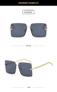 Detail of square oversized gray sunglasses with gold chain-link decorative temples