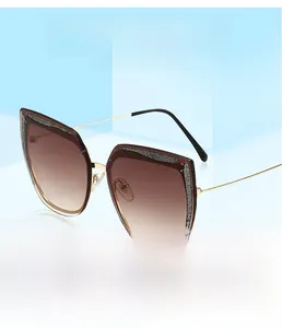 Dettaglio di occhiali da sole cat-eye con montatura glitterata e lenti sfumate