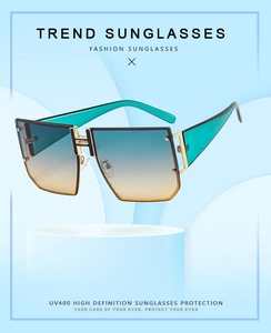 Detail of oversized polygon sunglasses with green legs and gradient lenses on a blue wave