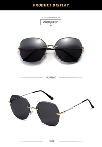 Detail view of gold metal wavy temples and grey lenses on rimless sunglasses