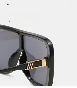 Macro detail of oversized black sunglasses with polished frames and gold metal hinges