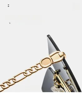 Detail of square sunglasses featuring bold gold chain temples and grey gradient lenses